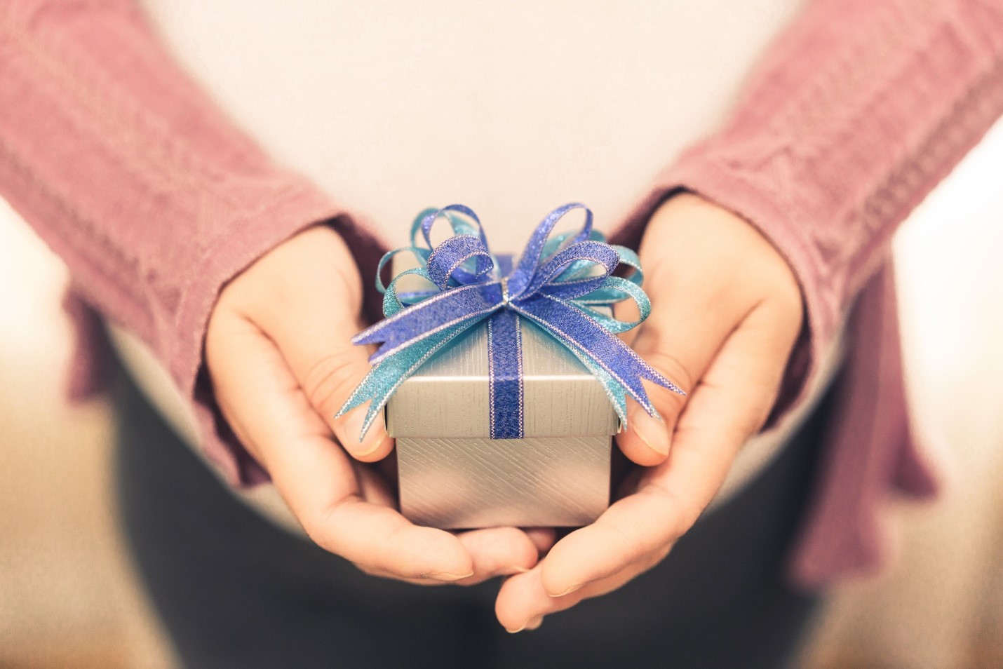 A woman holding a small gift with two hands